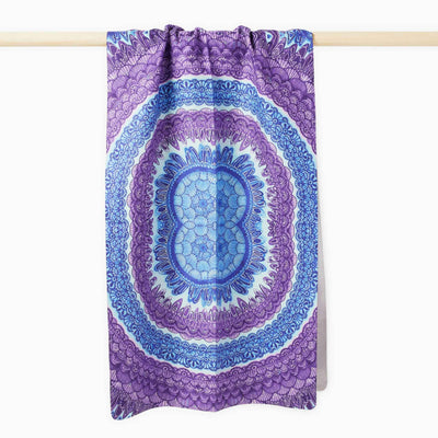 asana print yoga towel hanging over wooden bar. blue and purple detailed kaleidoscope design